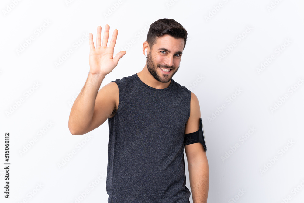 Fototapeta premium Young sport handsome man with beard over isolated white background saluting with hand with happy expression