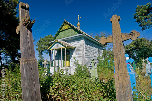 Wooden church and grave crosses in cemetery photo