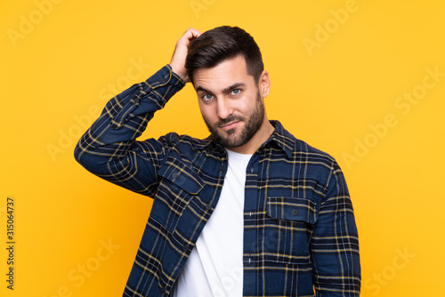 Young handsome man with beard over isolated yellow background with an expression of frustration and not understanding