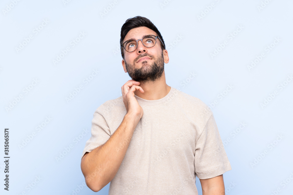 Young handsome man with beard over isolated blue background thinking an idea Young handsome man with beard over isolated blue background thinking an idea