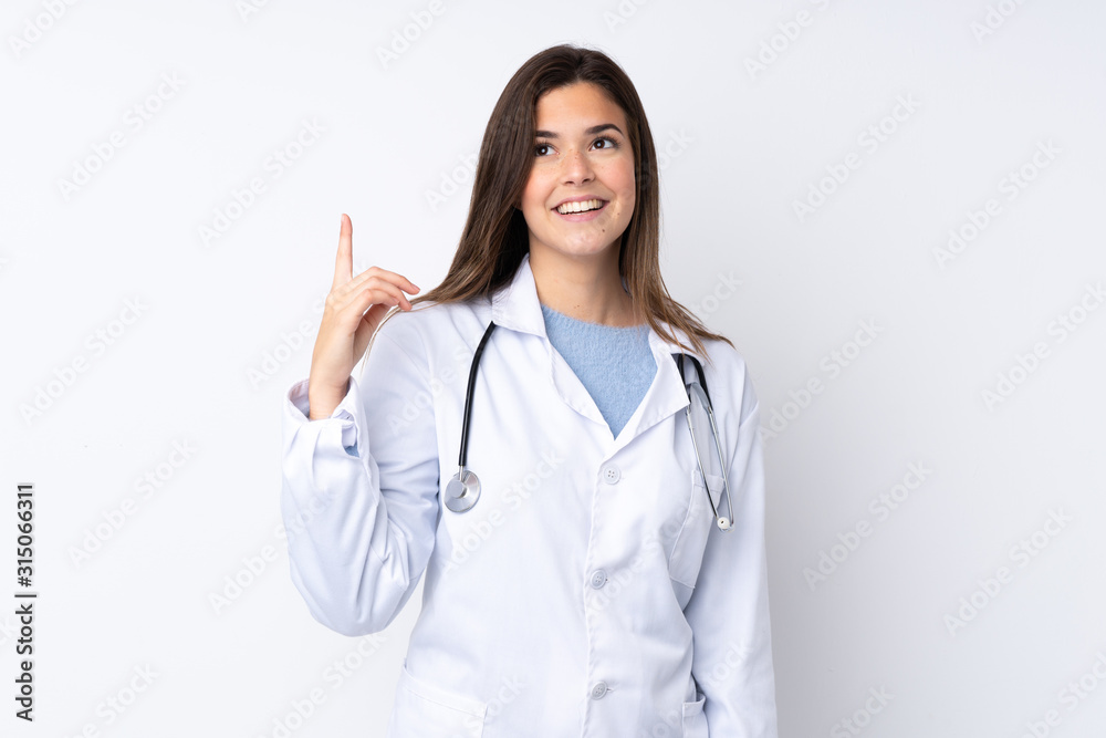 Teenager girl over isolated white background wearing a doctor gown and pointing up Teenager girl over isolated white background wearing a doctor gown and pointing up