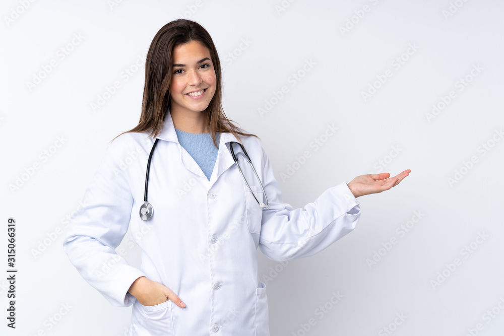 Teenager girl over isolated white background wearing a doctor gown and presenting something Teenager girl over isolated white background wearing a doctor gown and presenting something