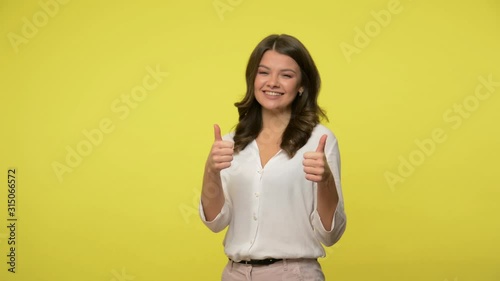 Well done, good job! Excited joyful brunette woman in blouse smiling cheerfully and showing double thumbs up, cool gesture, approving suggestion. indoor studio shot isolated on yellow background