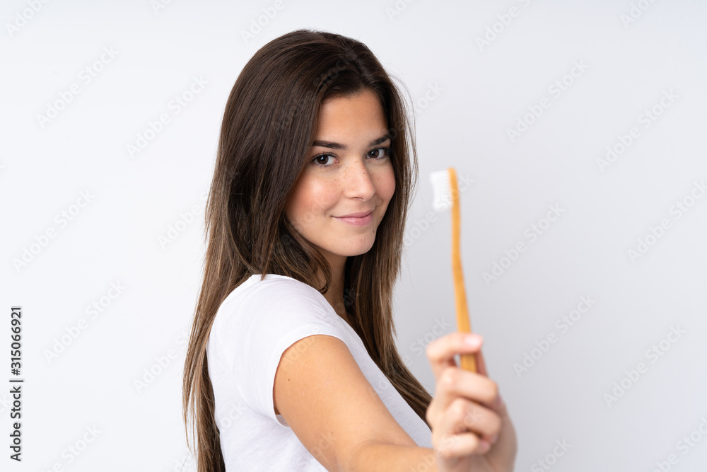 Teenager girl over isolated background with a toothbrush Teenager girl over isolated background with a toothbrush