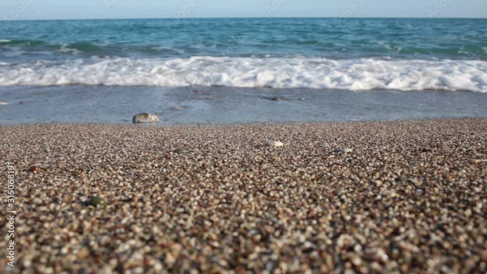 Low angle video shoot of blue sea water splashing at stony beach outside. Turkey. Natural background. Real time full hd footage.