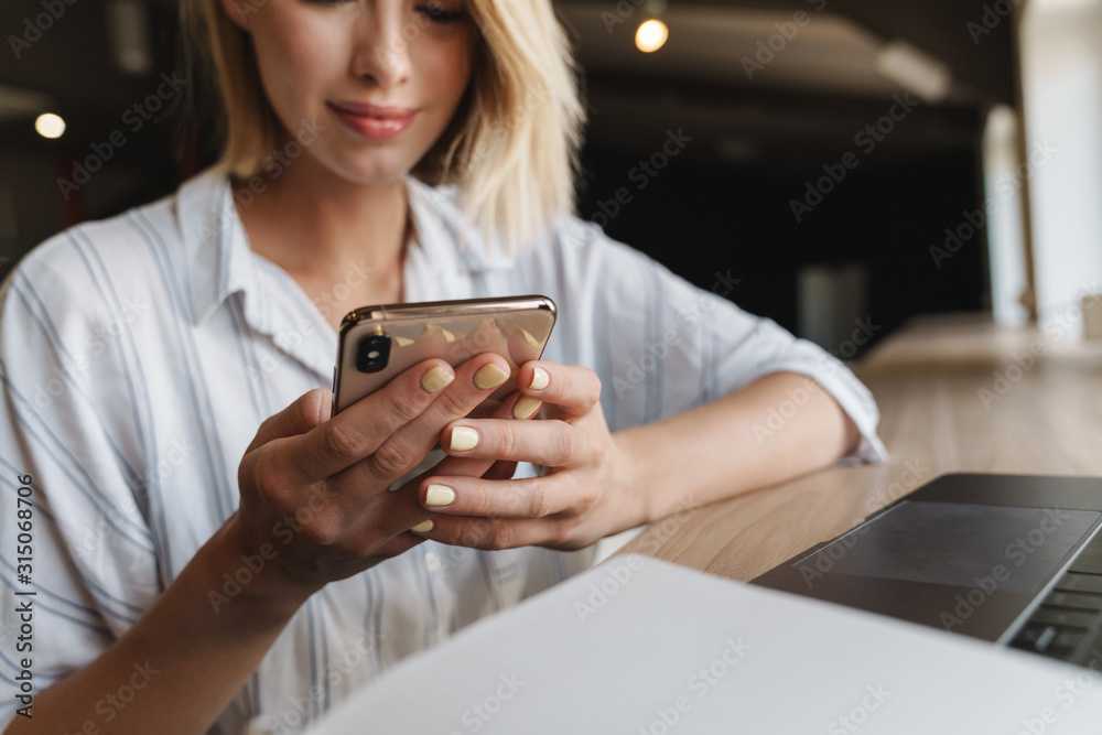 Photo of focused blonde woman typing on cellphone while working Photo of focused blonde woman typing on cellphone while working
