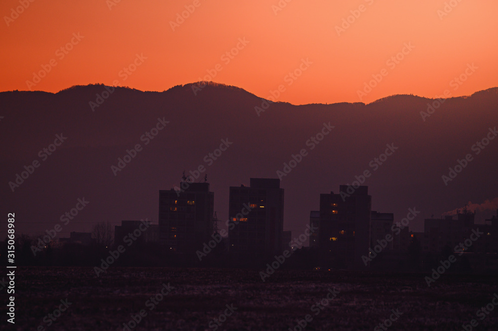 Block of flats silhouette in orange sunrise light. City in the morning