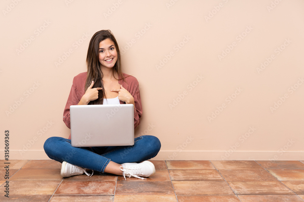 Teenager student girl sitting on the floor with a laptop with surprise facial expression Teenager student girl sitting on the floor with a laptop with surprise facial expression