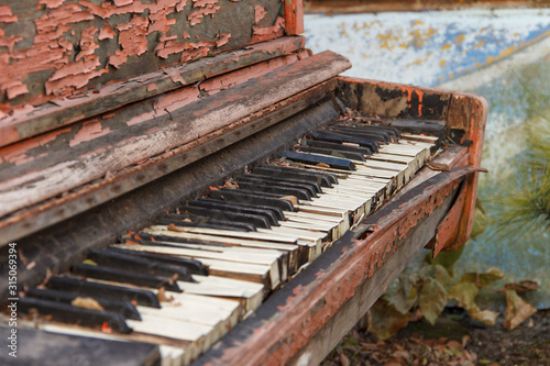 An old broken piano in the street with a large pan with white and black keys.