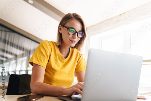 Photo of beautiful young woman working on laptop while sitting