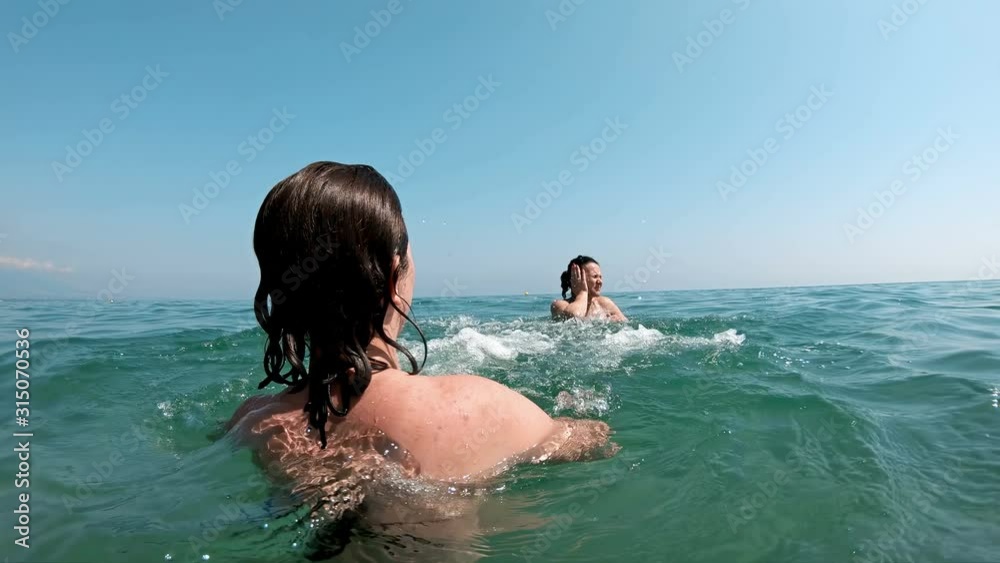 Daughter teasing mother and splashing her in the sea, slow motion Daughter teasing mother and splashing her in the sea, slow motion
