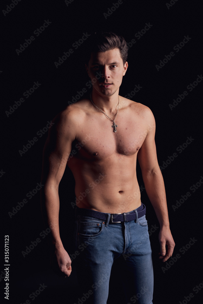 barechested guy with a dramatic light in the Studio. look at the camera seriously barechested guy with a dramatic light in the Studio. look at the camera seriously
