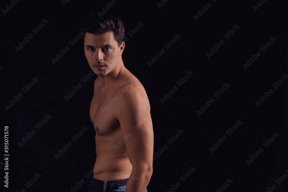 barechested guy with a dramatic light in the Studio. unfolds on camera