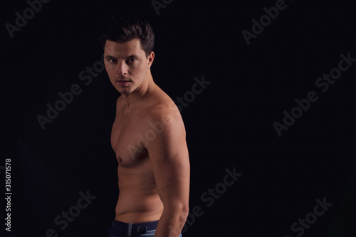 barechested guy with a dramatic light in the Studio. unfolds on camera