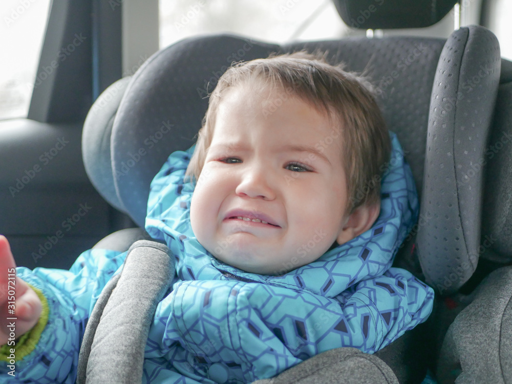 The child does not like to ride in a car seat. Dissatisfied child in a