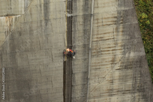 Homme escaladant la paroie d'un barrage