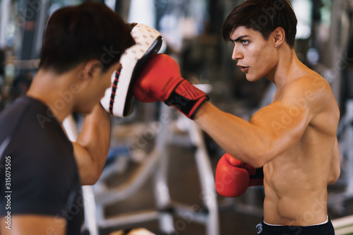 Fototapeta Trener thai trenuje boksera męskiego z rękawicą bokserską na siłowni, fitness, obóz bokserski.
