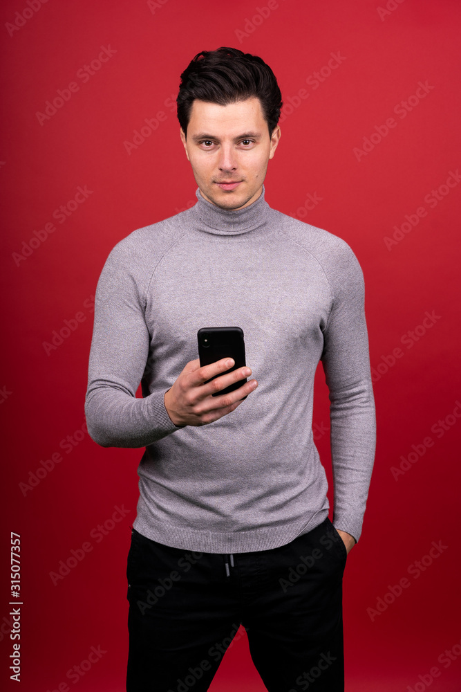 The guy with The smartphone in his hands reads the feed and looking at camera The guy with The smartphone in his hands reads the feed and looking at camera