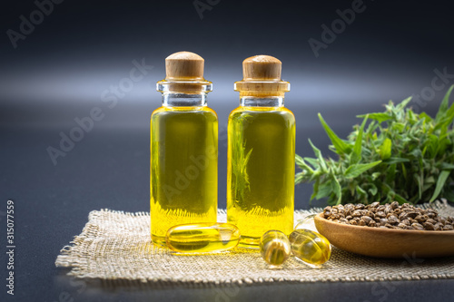 Fototapeta Naklejka Na Ścianę i Meble -  Hemp oil products in small bottles placed together. CBD hemp oil is extracted from black background fresh hemp extract. Herbs and recreation herbs have space for entering text.