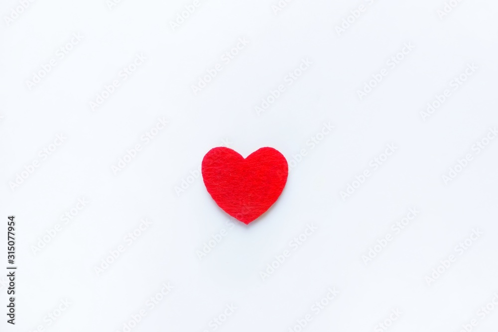 Red heart made of felt on a white background. Valentine's day symbol, holiday concept, minimal style. Top view with copy space for text.