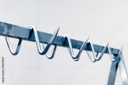 Tableau sur toile Metal meat hook or hangers in a row in a butchery slaughter house