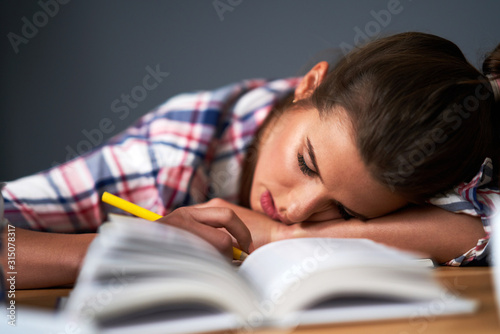 Tired female student learning till late at home