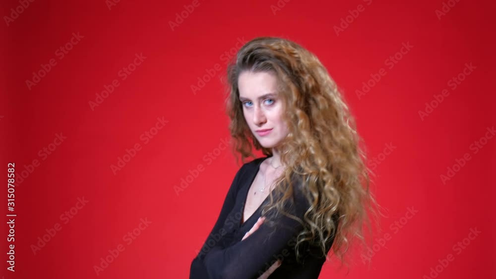 Red-haired girl with curly long hair on a red background. Black blouse, flirts, smiles, gets upset with braces and winks. Red-haired girl with curly long hair on a red background. Black blouse, flirts, smiles, gets upset with braces and winks.
