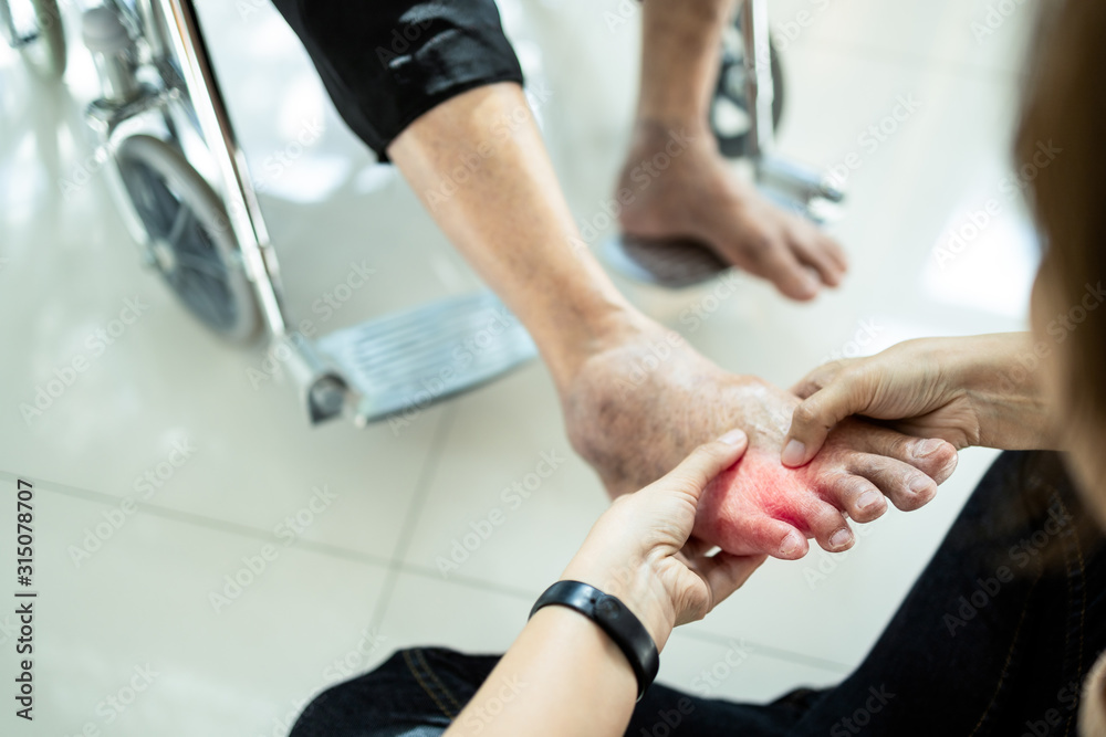 Asian senior mother in wheelchair,receiving a foot massage from her daughter,physiology pressing with fingers to relax,old woman enjoy,pain relief,elderly people suffer from sore muscles,achy leg