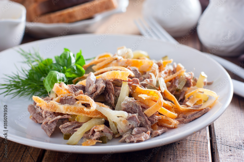Minced salad of boiled beef and egg pancakes on a white plate, selective focus Minced salad of boiled beef and egg pancakes on a white plate, selective focus