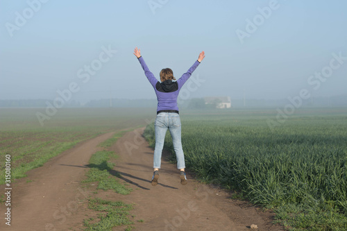 Happy woman traveler jumps among fields  beautiful misty morning