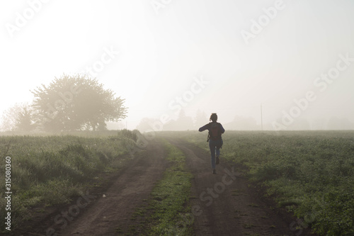 Back view of a woman traveler who walks in nature very beautiful atmospheric misty morning © Victoriia