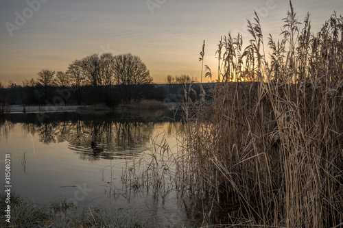 Sonnenaufgang über einem kleinen See an einem Wintermorgen
