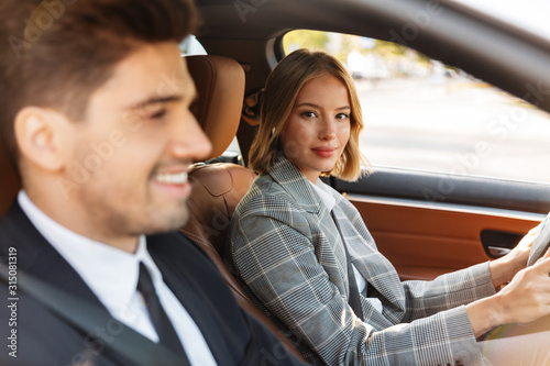Image of young caucasian businesslike man and woman riding in car