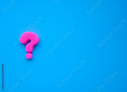 pink question mark on a blue background. Background photo with place for text.