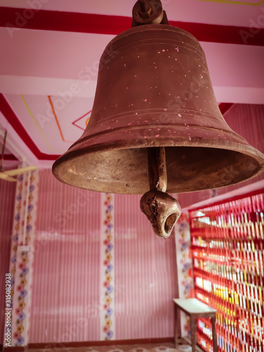 Bronze bell kept in a temple with pink in background.. photo