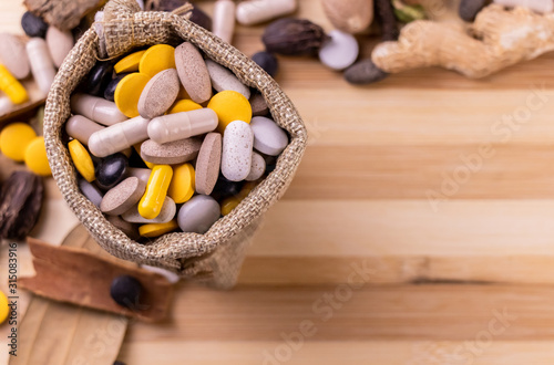 Top view macro shot of herbal pills and tablets arranged with spices on a red stone. Unani medicines concept. photo