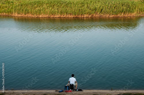 single man fishing on the blue river side