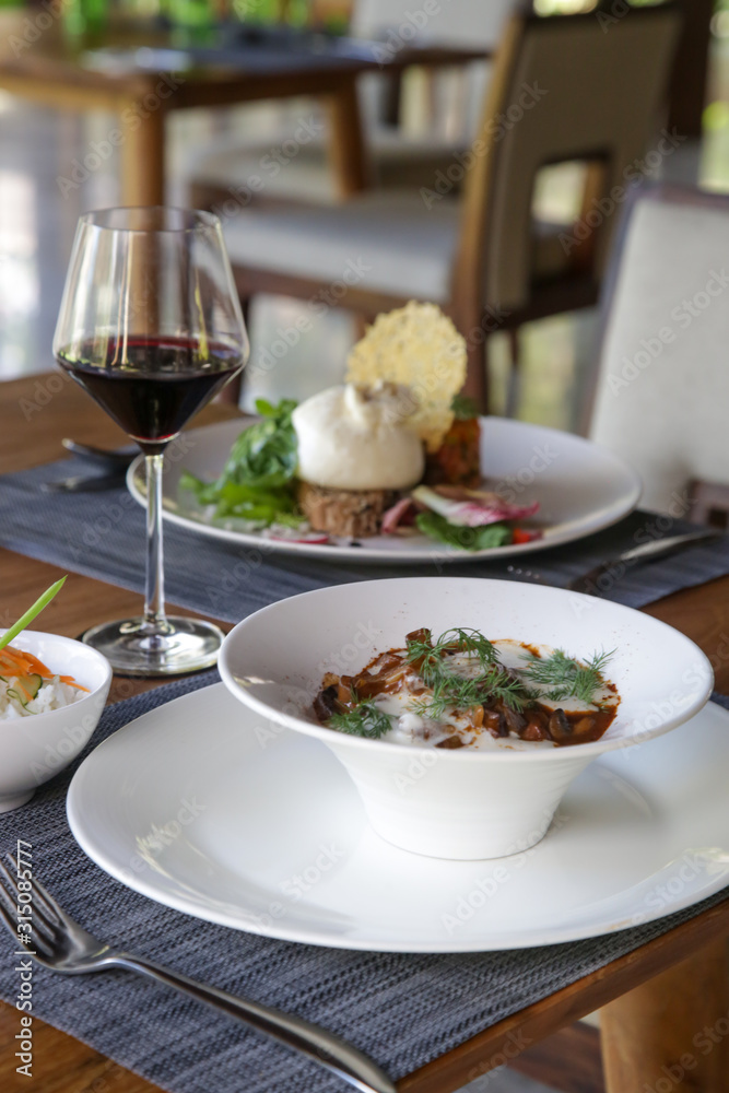 Beautifully decorated meals and a glasses of wine on the wooden table Beautifully decorated meals and a glasses of wine on the wooden table
