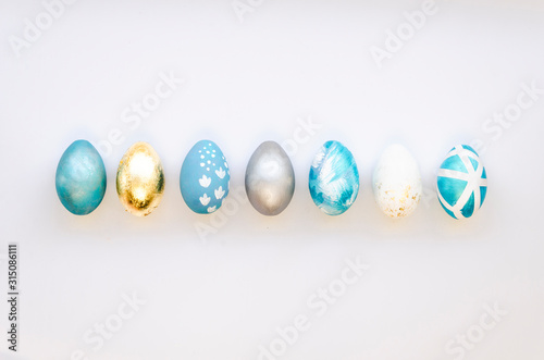 Stylish Set of 7 blue, silver and gold Easter eggs isolated on white background Ester concept. Flat lay