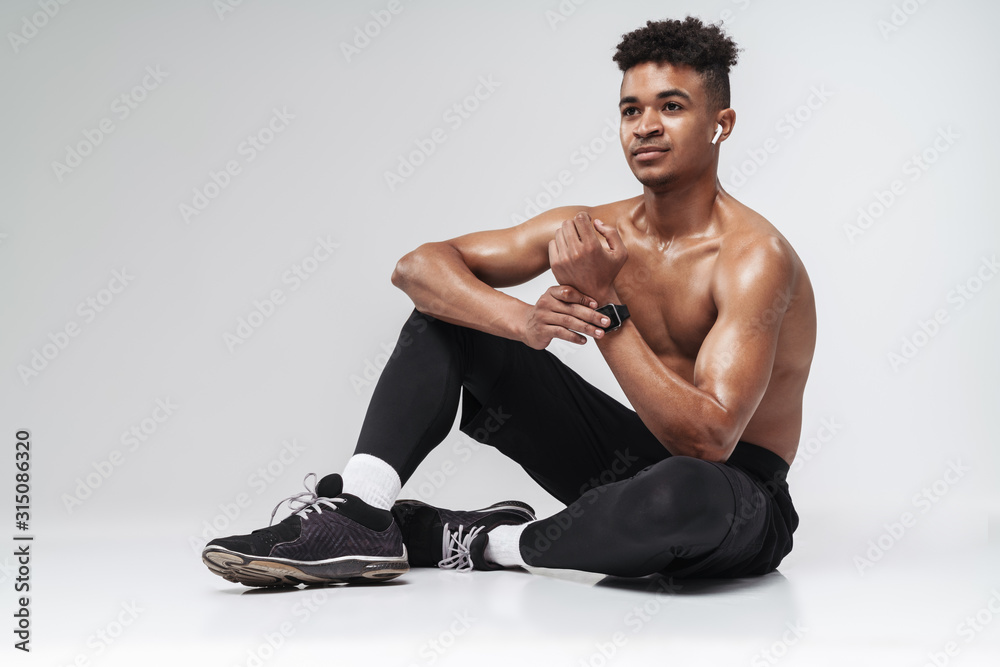 Photo of shirtless african american man using earpods and smartwatch Photo of shirtless african american man using earpods and smartwatch