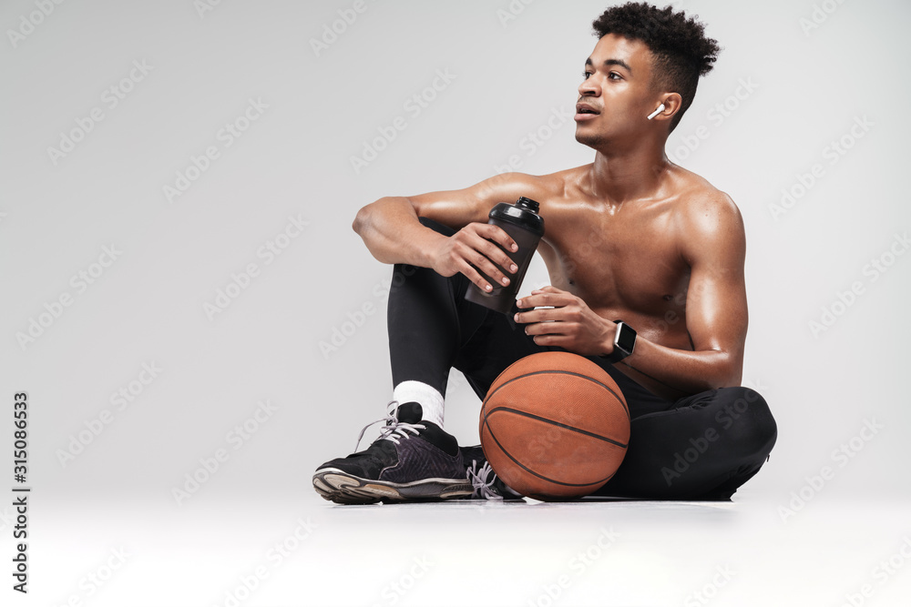 Photo of african american man using earpods and drinking water Photo of african american man using earpods and drinking water