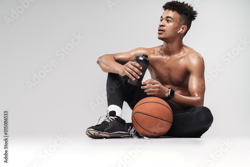 Photo of african american man using earpods and drinking water photo