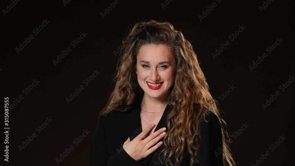 Red-haired girl with curly long hair on a black background. Black blouse, book, reading6 smiles, gets upset with braces and winks. Red-haired girl with curly long hair on a black background. Black blouse, book, reading6 smiles, gets upset with braces and winks.