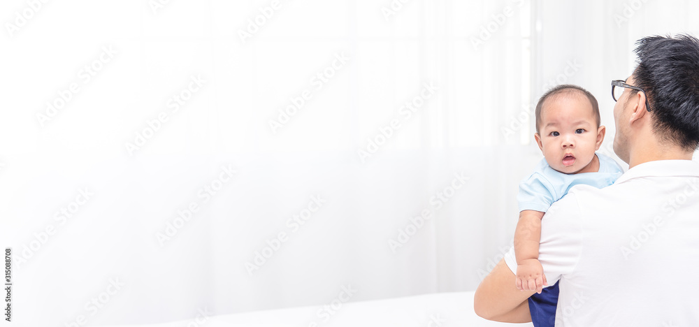 Young Assian father holding his baby 5 months newborn. Father tatking care of baby on the weekend.