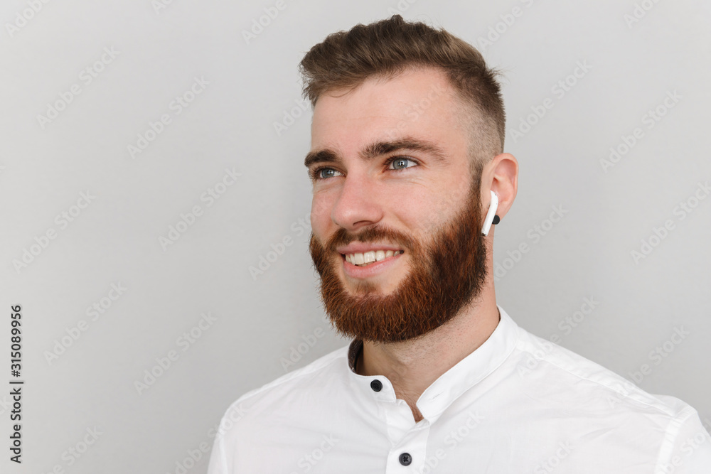 Obraz premium Image of cheerful handsome man smiling and using earpod