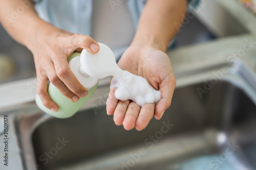 Close up of woman hand take cleaner foam from pump foam cleanser bottle