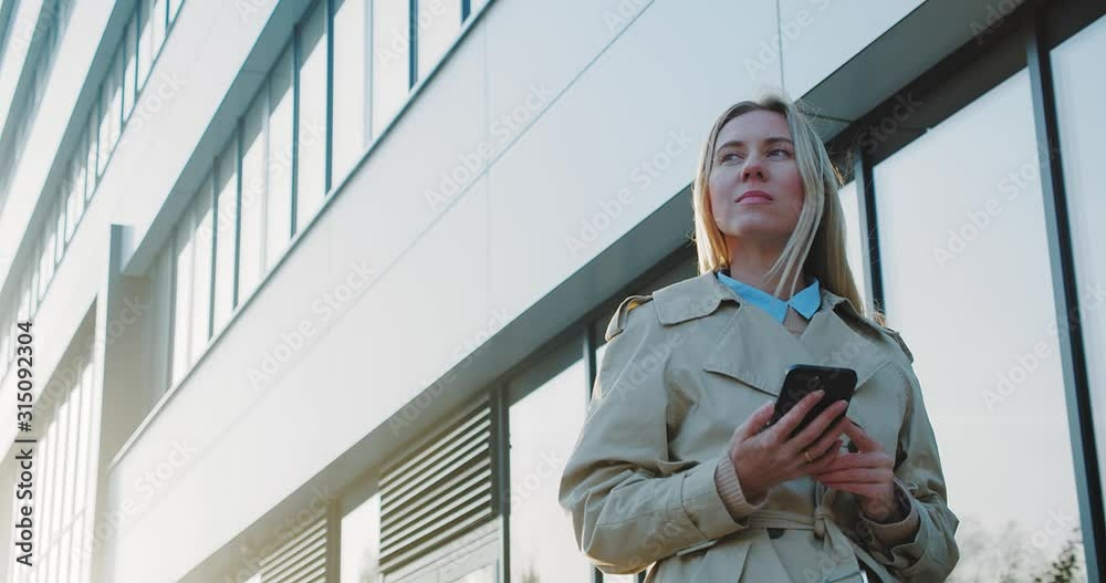 Attractive business woman smiling portrait. Young business people confident pretty. Female goes with smartphone in the city. Growing, success. 4K slow motion video Attractive business woman smiling portrait. Young business people confident pretty. Female goes with smartphone in the city. Growing, success. 4K slow motion video