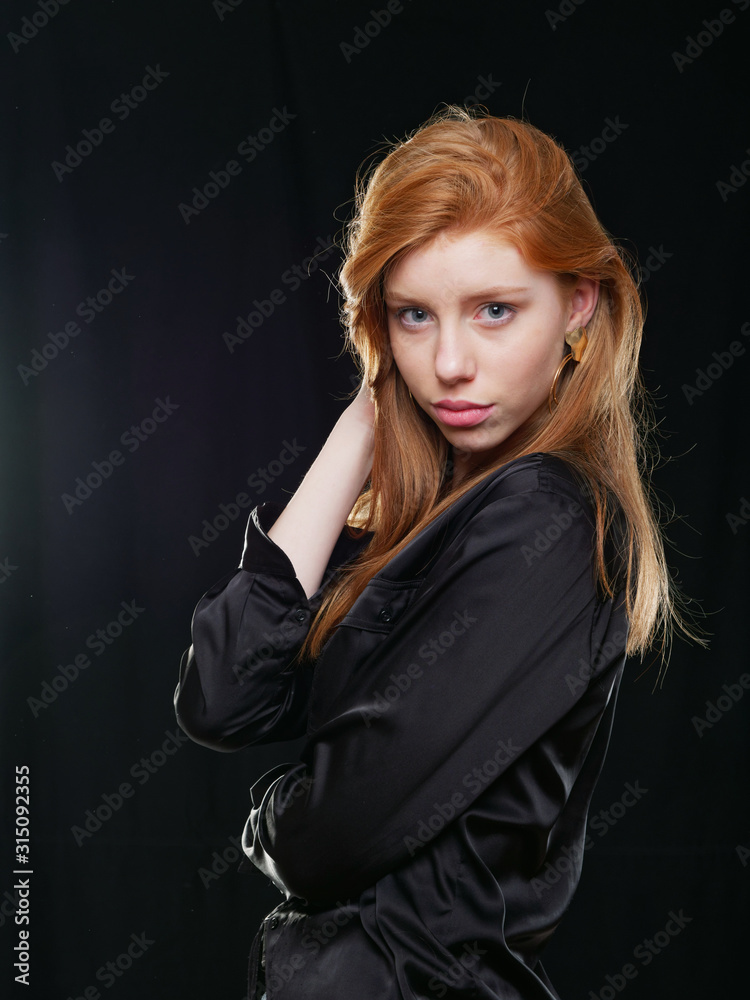 Fototapeta premium young girl with long red hair on a black background