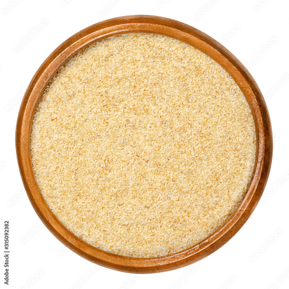 Dried garlic granules in wooden bowl. Allium sativum, with its pungent flavor is used as seasoning or condiment and also in medicine. Isolated macro food photo, closeup from above on white background.