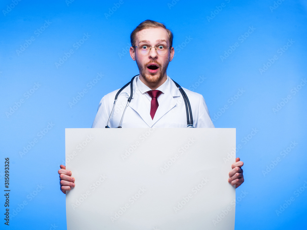 Surprised doctor with a sheet of white paper in his hands. The concept of urgent news and discoveries in medicine. Surprised doctor with a sheet of white paper in his hands. The concept of urgent news and discoveries in medicine.